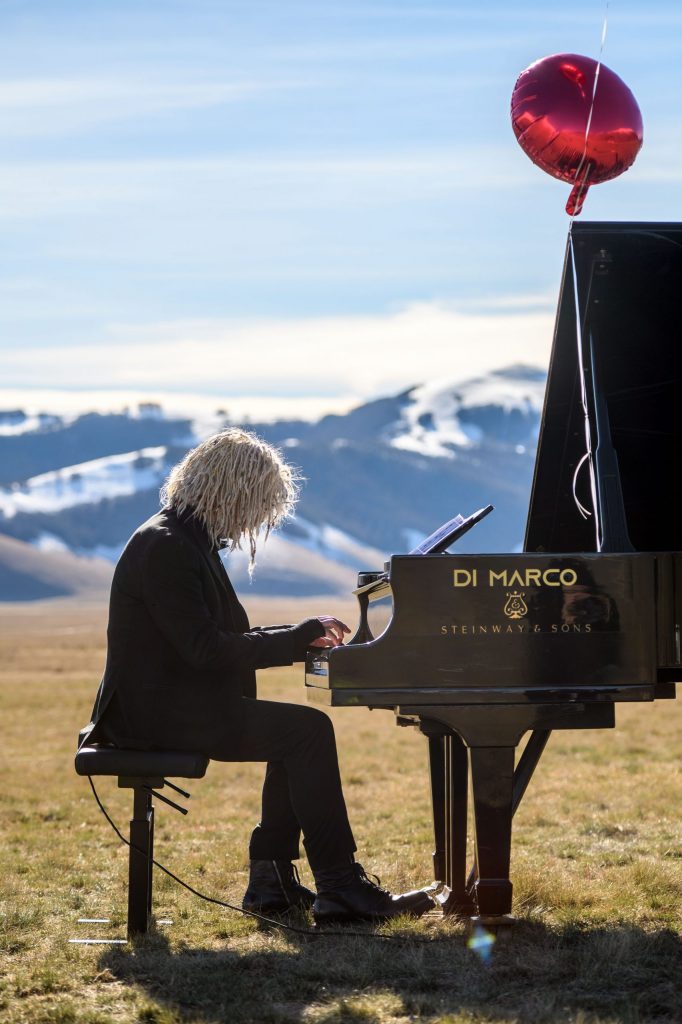 Pianista Mastrini suona pianoforte per Smartpeg a coda nella piana di Castelluccio con sfondo le montagne innevate