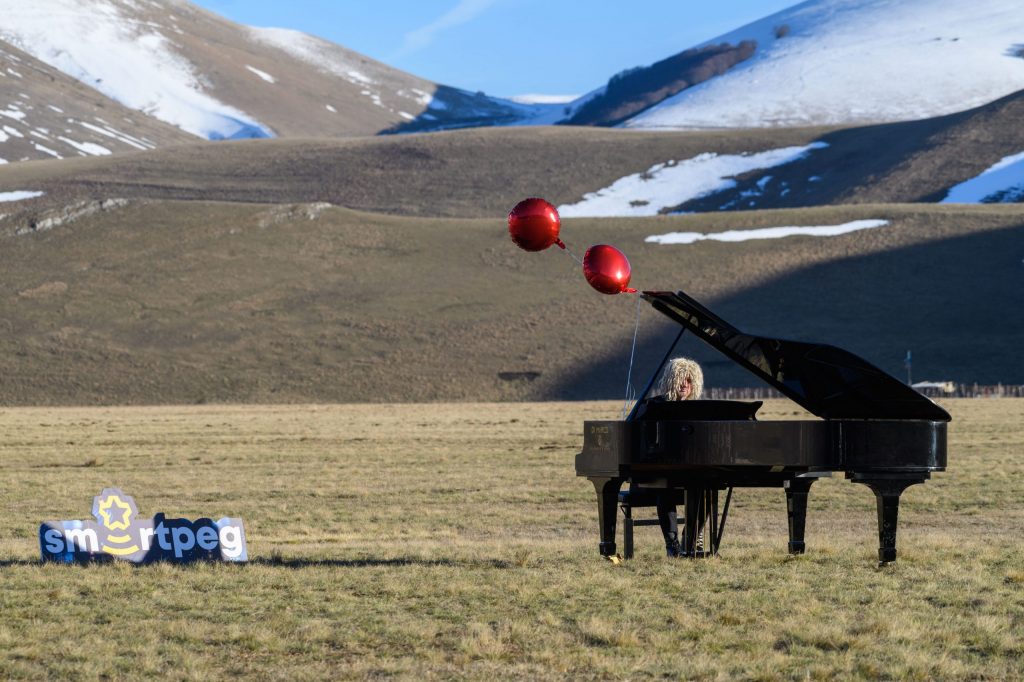 Pianista Mastrini suona pianoforte per Smartpeg a coda nella piana di Castelluccio con sfondo le montagne innevate